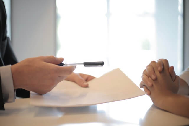 Person holding paper and pen in front of client
